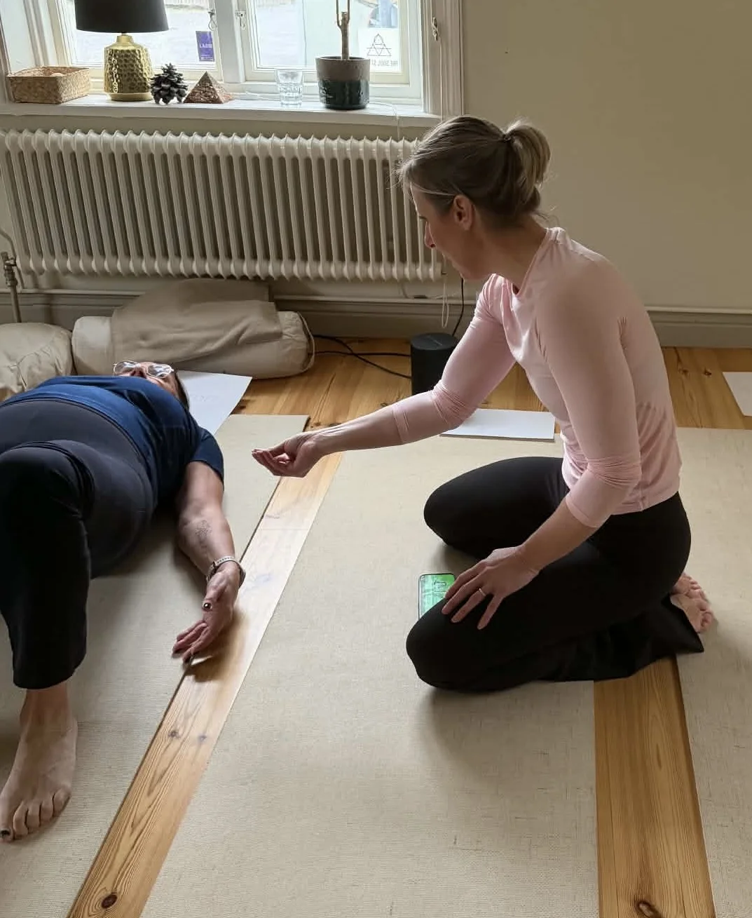 Malin sitter bredvid en deltagare och vägleder under en healingstund